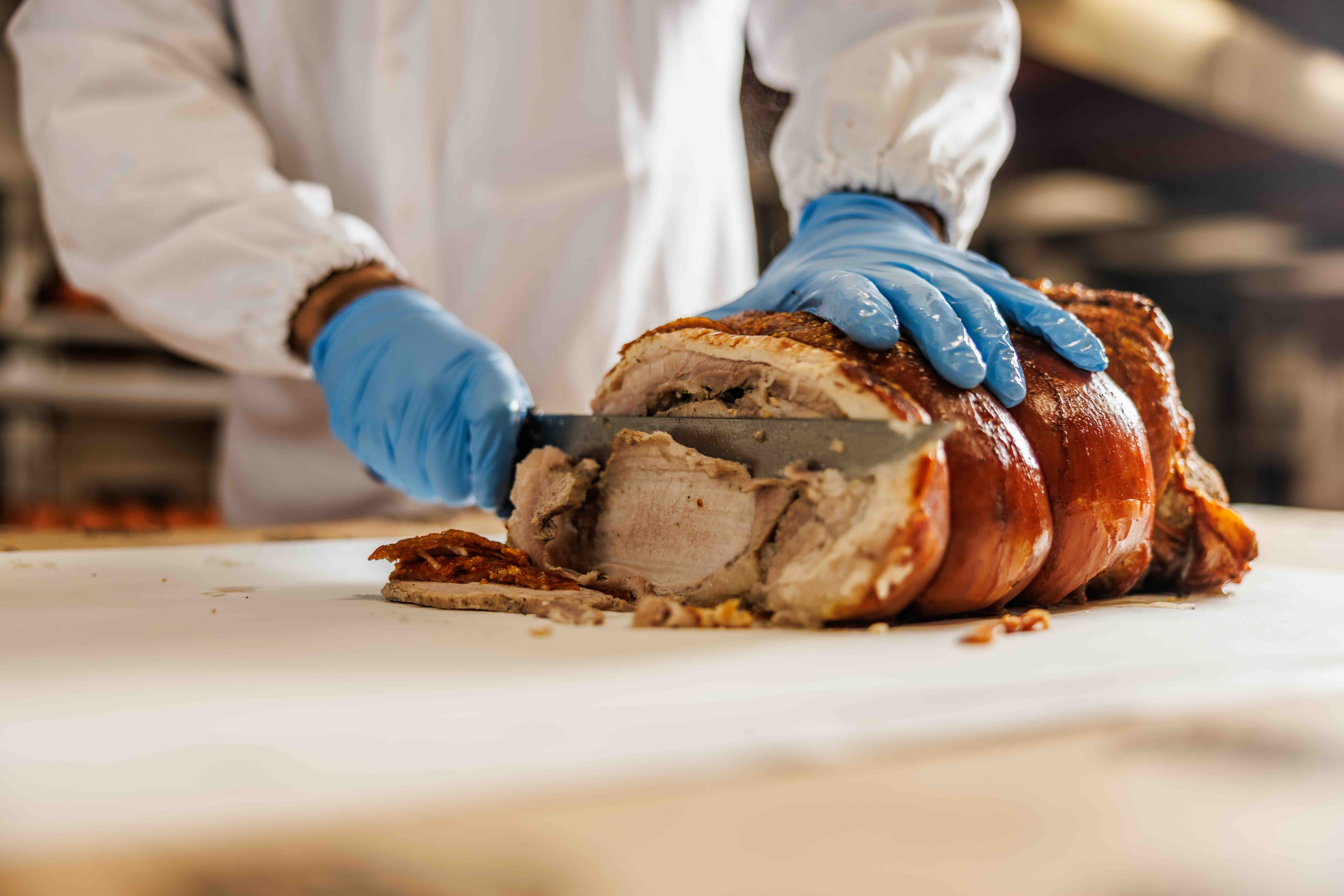 Mani che tengono un tronchetto di porchetta di Ariccia tagliato